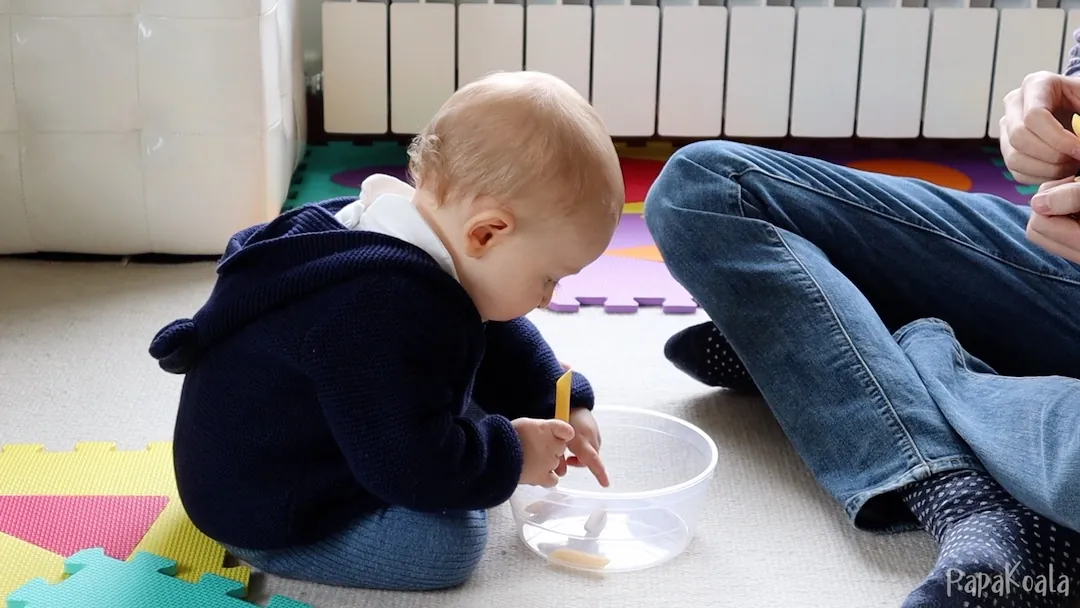 You show them how to drop macaroni into a container, and they practice opening their hand right over it.